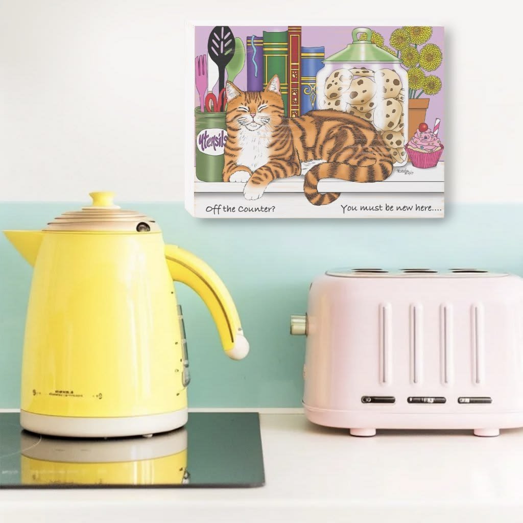old yellow teapot and ink poster wit funny sign on it about a cat